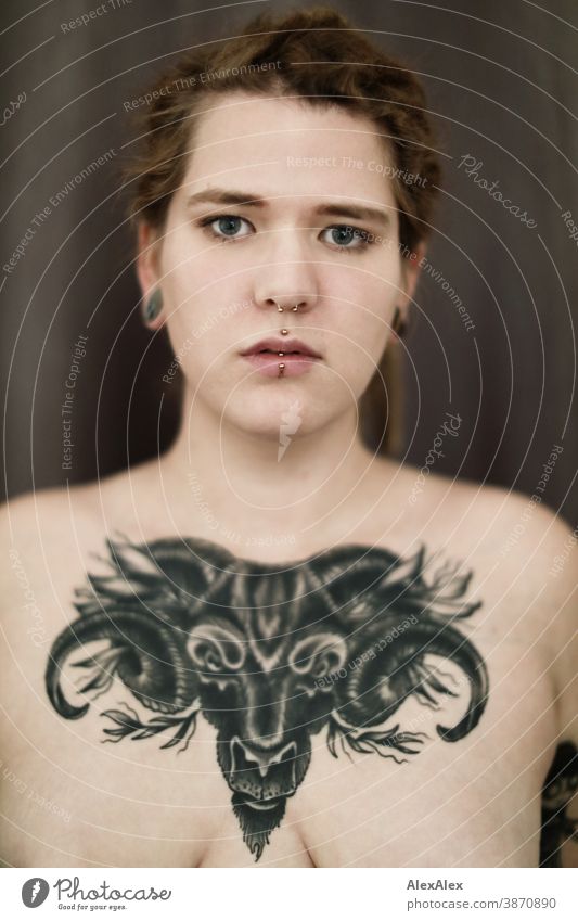 Portrait of a young woman, who has a large tattoo of an ox head on her décolleté Woman Dirty Blonde tattooing Jewellery Piercing earring Chest Upper body