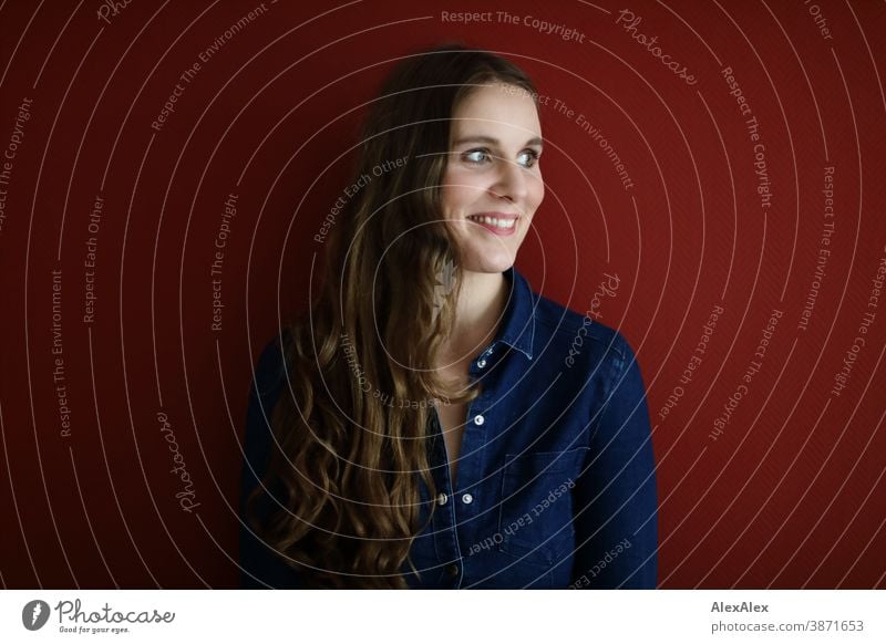 Portrait of a young woman in front of a red wall Woman Slim pretty Brunette long hairs Shoulder Face smart emotionally see look Looking Direct naturally