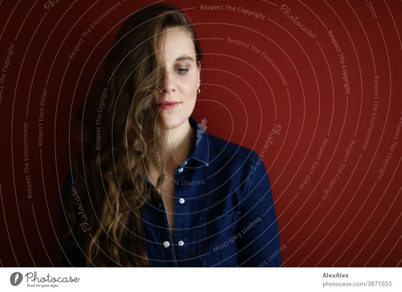 Portrait of a young woman in front of a red wall Woman Slim pretty Brunette long hairs Shoulder Face smart emotionally see look Looking Direct naturally