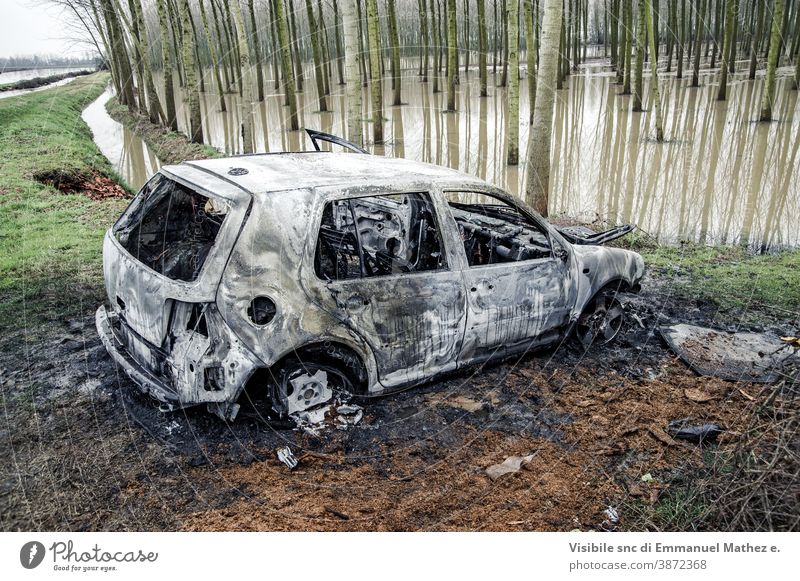 burnt out car abandoned near a flooded poplar grove danger smoke fire accident trouble hot flammable pollution rubbish vandalism land vehicle exploding