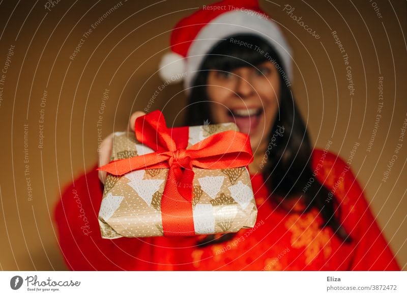 Woman in Santa's cap joyfully presents a Christmas present Christmas gift Donate Santa Claus hat Giving of gifts Joy Euphoric excited Christmas & Advent Gift