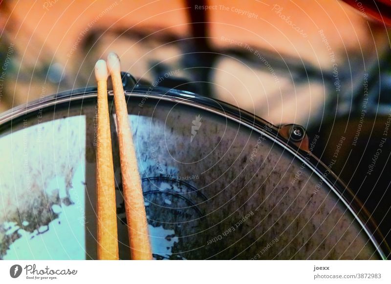 Drumsticks rest on snare drum with heavily worn skin, weak depth of field play drums Break wooden sticks Tympanic membrane Snare Pelt Drum set Rhythm