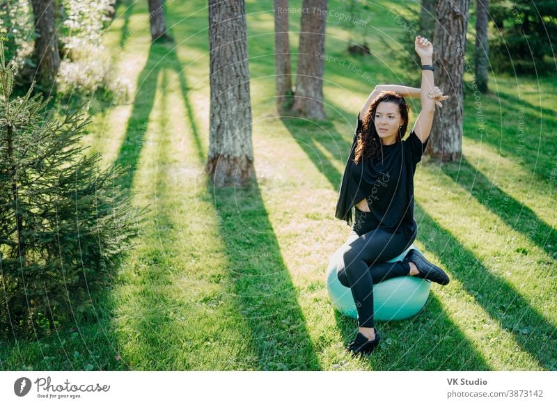 Outdoor shot of active brunette woman in sportswear poses on yoga