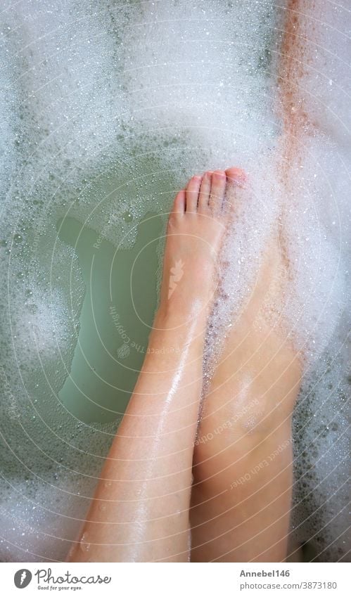 Women's legs in the bathtub, bathing with bubble bath foam top view, relaxtion beauty spa concept care hygiene soap body young bathroom relaxation water female