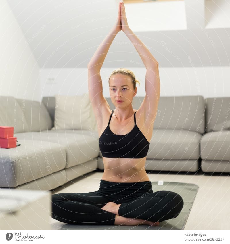 Beautiful blonde woman doing home workout indoors. Woman practice yoga at  home. Fit girl using workout tutorials for healthy active lifestyle. Woman  using quarantine for home workouts. - a Royalty Free Stock