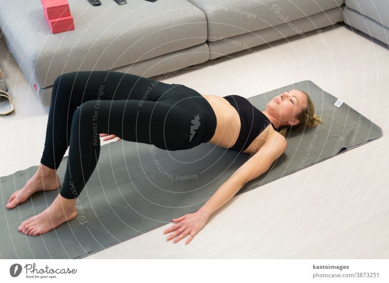 A young woman sits on a yoga mat and rests after a workout. Sports