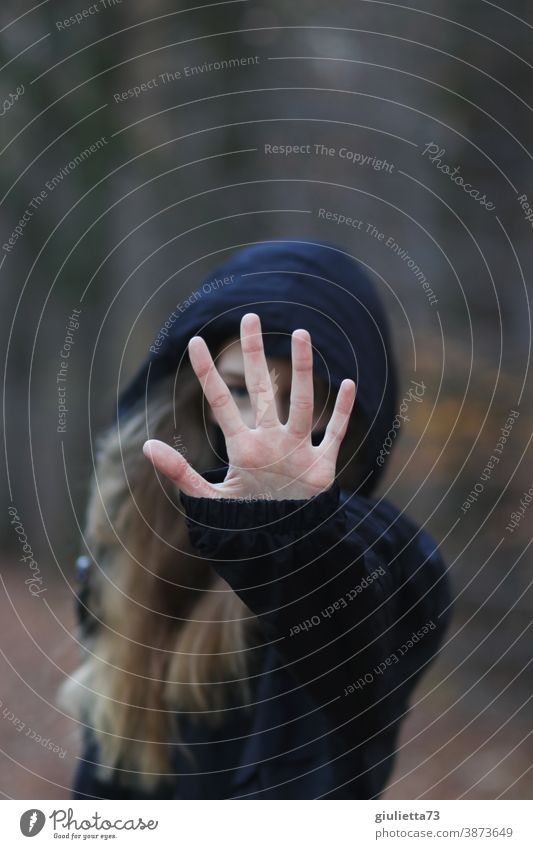 Young woman symbolizes: No - Stop - Halt , by stretching out her hand in front of her Risk of infection corona covid-19 coronavirus show limits