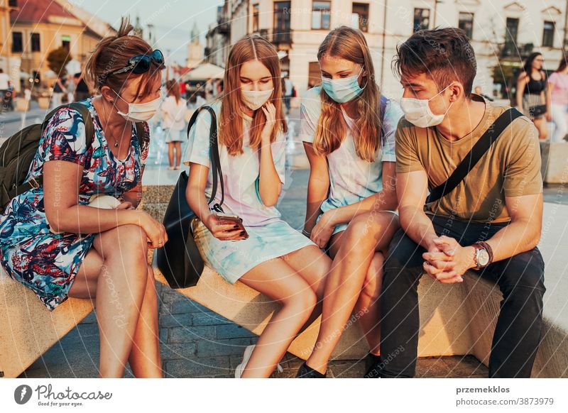 Young women spending time together sitting in the city center wearing the face masks to avoid virus infection caucasian conversation covid-19 female lifestyle
