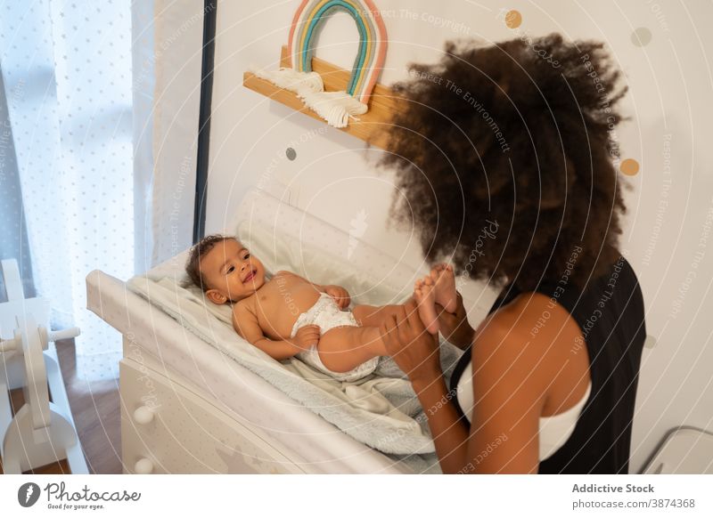 Black woman playing with cute baby on changing table change diaper mother tender playful toddler nappy care ethnic black african american lying home child