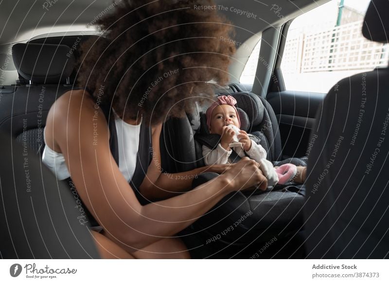 Black mother fastening belt on baby car seat buckle up toddler safety ethnic black african american passenger care backseat parent cute vehicle child transport