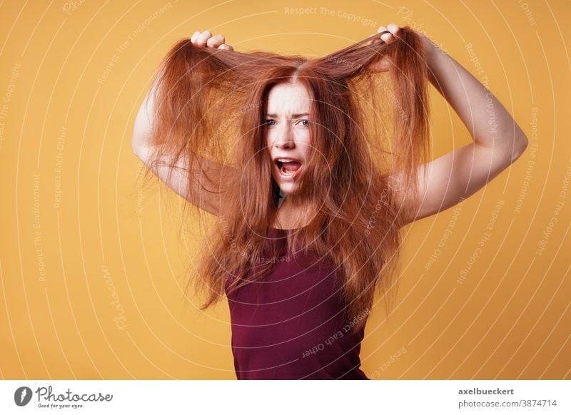 frustrated young woman pulling and tearing her hair bad hair day long red care frustration scream emotion messy unkempt disheveled tantrum funny hairstyle
