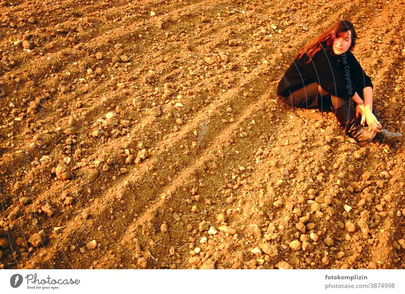 Young woman sitting on arable land Woman acre Arable land Earth look out portrait Feminine Long-haired Personality long hairs Self-confident Identity Nature