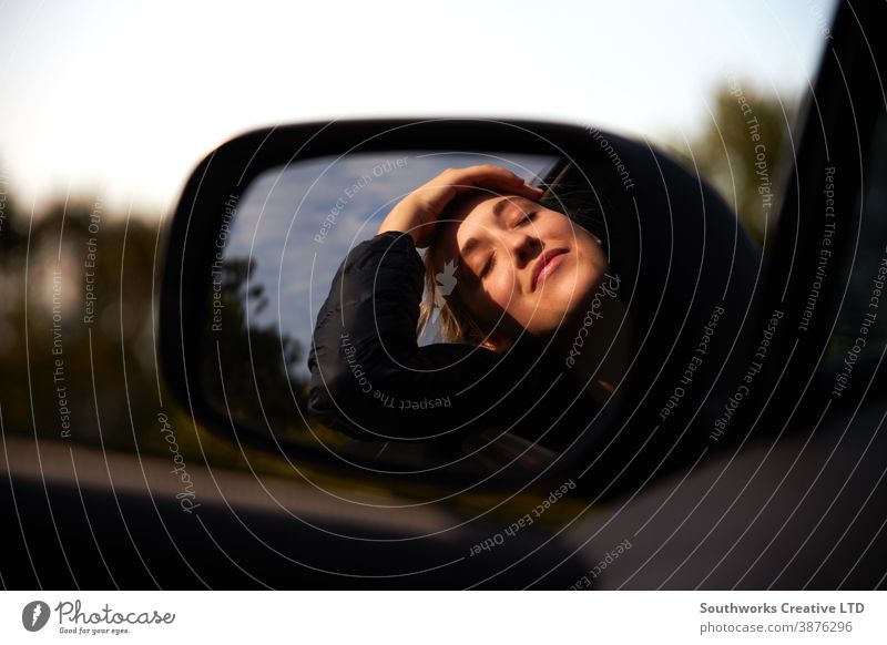 Reflection In Driving Mirror Of Young Woman On Road Trip Vacation Leaning Out Of Rental Car Window road trip car car hire woman young women holiday vacation