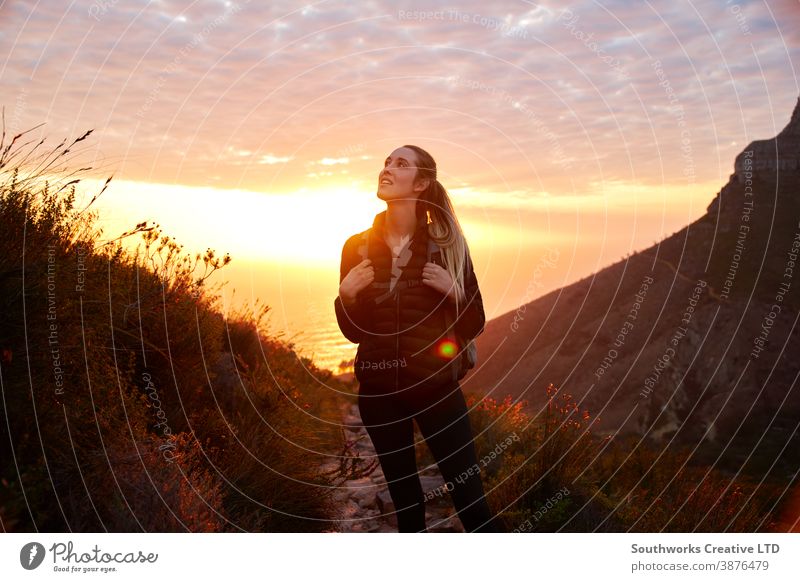 Front View Of Young Woman With Backpack Setting Off For Hike Along Coastal Path At Sunset adventure sunset sunrise woman golden hour young women hike hiking