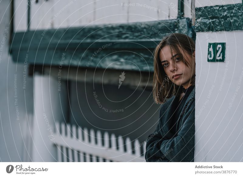 Young woman standing near building in city street emotionless lean old melancholy female mood serious young cloudy overcast town exterior trendy tranquil