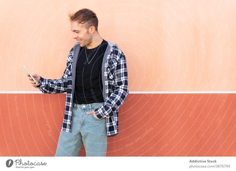 Cheerful hipster man using smartphone casual cheerful message modern gadget checkered shirt mobile content young male device browsing connection communicate