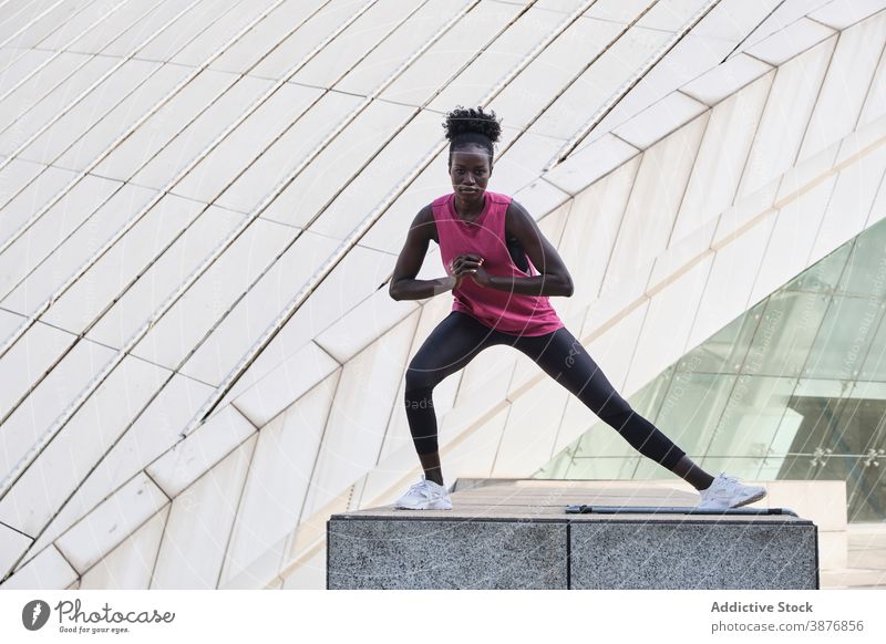 Athletic black woman doing exercises on street - a Royalty Free