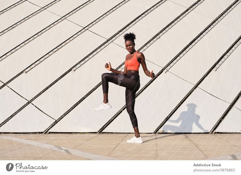Athletic black woman doing exercises on street - a Royalty Free