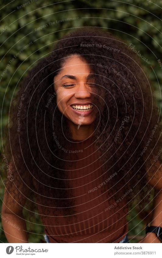 Happy ethnic woman in green garden charming smile natural beauty candid curly hair afro hairstyle park female black african american young happy cheerful joy