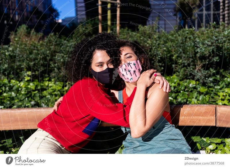 Lesbian couple with sunglasses embracing and relaxing on a park bench woman lesbian bonding person homosexual love lifestyle hug female mask coronavirus