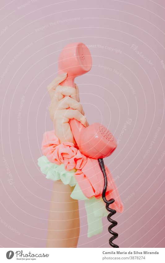 female hand holding an old pink phone on pink background. antique business cable call call for you classic communication concept connection copy space dial girl