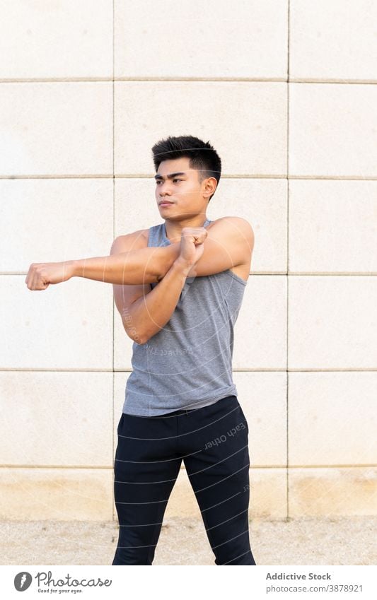 Determined ethnic sportsman warming up during workout warm up stretch street muscular determine athlete male asian active training healthy physical vitality