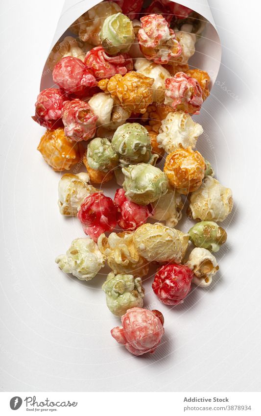 Delicious crispy popcorn on white table colorful sweet treat snack paper cone delicious multicolored package heap food pile yummy nutrition appetizing gourmet