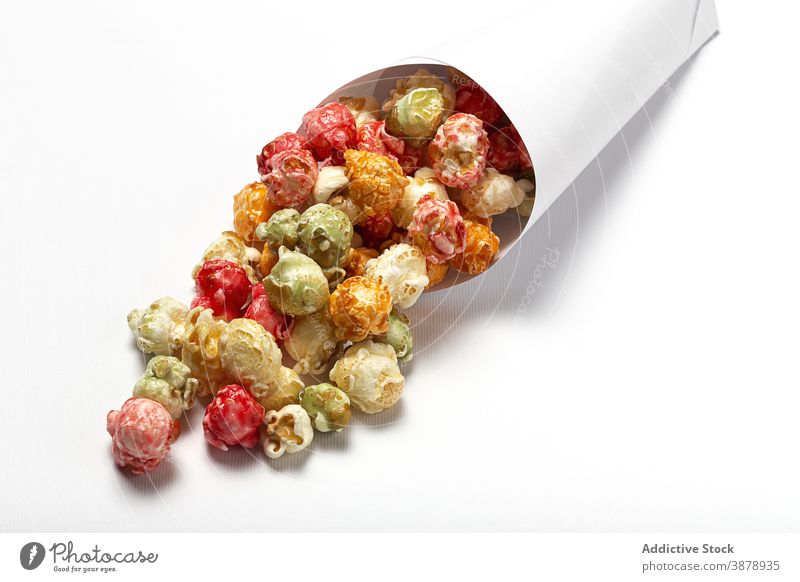 Delicious crispy popcorn on white table colorful sweet treat snack paper cone delicious multicolored package heap food pile yummy nutrition appetizing gourmet