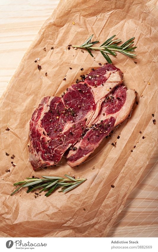 Rae beef steak with species on baking paper raw meat rib eye entrecote rosemary food uncooked cuisine parchment ingredient culinary gourmet meal protein natural