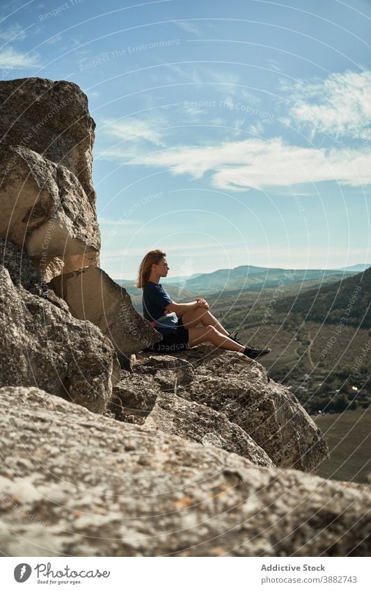 Traveling woman sitting on rock in highlands hiker mountain trekking viewpoint relax freedom enjoy hill female rocky adventure majestic scenery tourism summer