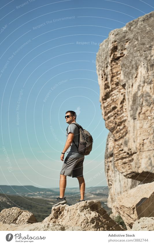 Man with backpack on rock in mountains traveler hiker man vacation summer wanderlust adventure highland male explorer spectacular picturesque landscape journey