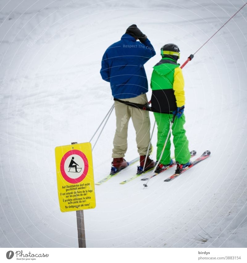 Father and child use ski lift, drag lift. Snow in the ski area. Sign that sledge drivers may not use the lift Skier Ski lift Ski tow Skiing Lift operation
