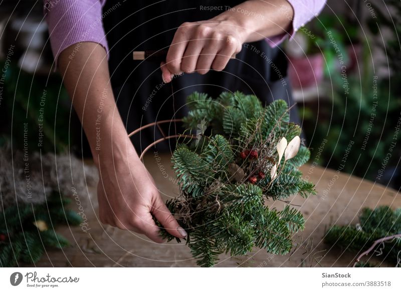 Woman making Christmas wreath of spruce, step by step. Concept of florist's work before the Christmas holidays. hand woman hands wooden table handicraft