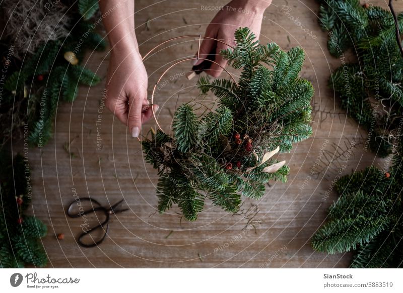 Woman making Christmas wreath of spruce, step by step. Concept of florist's work before the Christmas holidays. flat lay branches hand wooden table handicraft