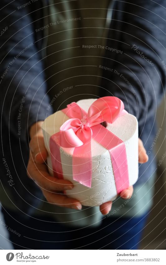Toilet paper roll with pink ribbon is handed over toilet paper Coil Gift Pink Bow Handover corona hoard Christmas Birthday Donate Christmas gift Giving of gifts