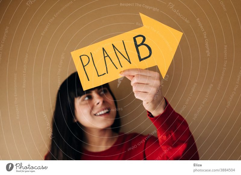 Positive-minded woman with an arrow with plan B written on it Plan B Orientation Arrow alternative Flexibility Optimism Alternative option make new arrangements