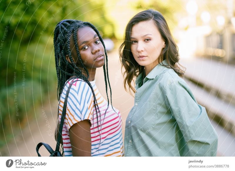 Two young friends looking at camera together on the street. Multiethnic women. multiethnic black afro girl student two fun people lifestyle smile female pretty