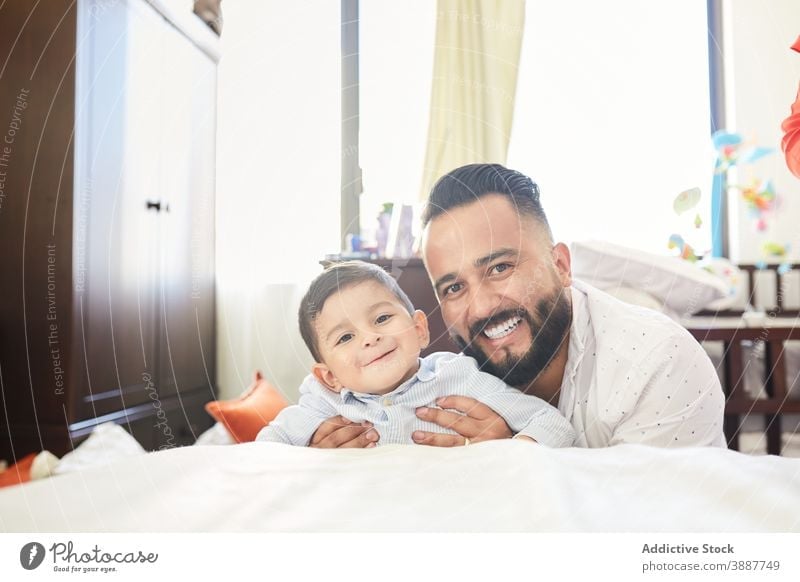 Cheerful man playing with cute toddler at home father having fun delight together fatherhood parenthood hispanic ethnic male kid little dad relationship child