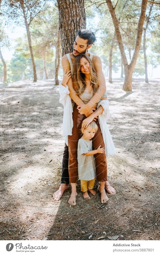 Happy multiethnic family hugging in forest woods weekend together toddler kid love unity multiracial diverse nature embrace relationship affection bonding