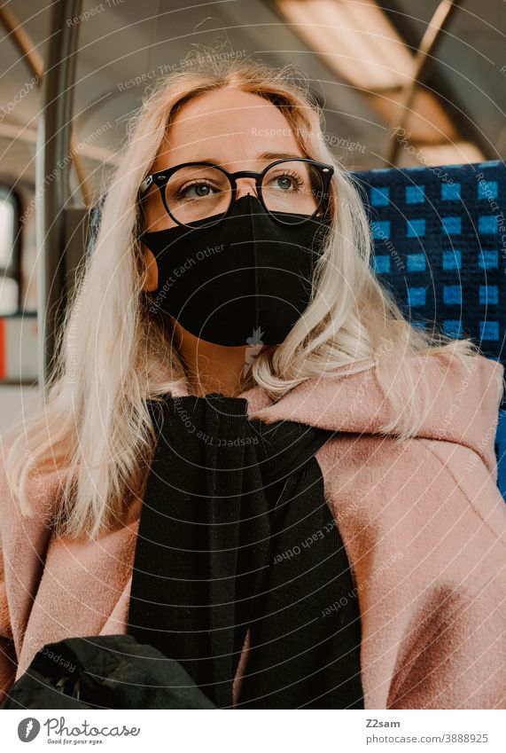 Young woman sitting in the train with a corona mask coronavirus Blonde long hairs Track voyage Company Winter Coat Eyeglasses Fashion style Looking pretty