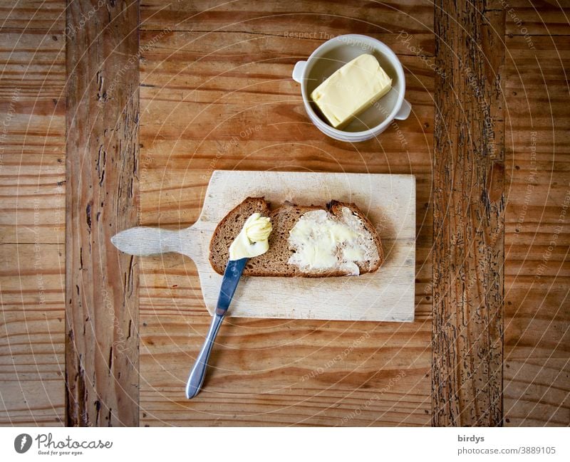 Bread and butter on vesper board on wooden table. Bird's eye view Butter snack Wooden table Knives Butter bowl Delicious Mixed-grain bread Authentic Brunch