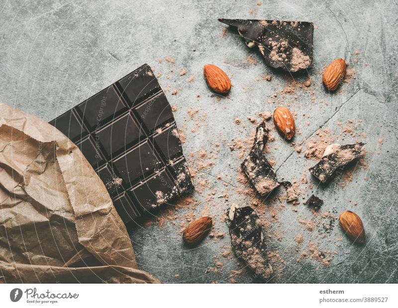 Dark chocolate bar and Broken chocolate pieces and almonds yummy confectionery envelope dark chocolate broken antioxidant cacao powder candy calorie eating