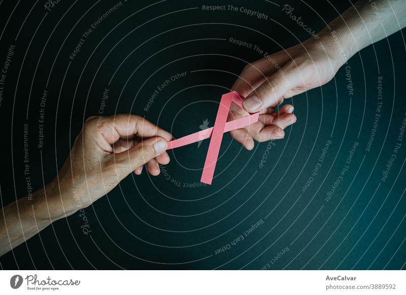 An old hand giving a pink ribbon to a young hand awareness symbol breast cancer blank charity cure ill trailing copy space survival celebrate month health care