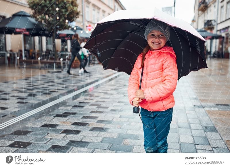 Little girl holding big umbrella walking in a downtown on rainy gloomy autumn day raining outdoors little seasonal fall childhood beautiful weather outside kid