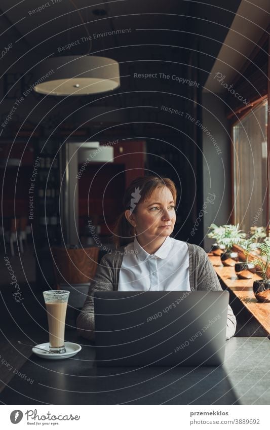 Businesswoman working remotely on her laptop managing her work sitting in a cafe business caucasian computer connection desk entrepreneur female indoors