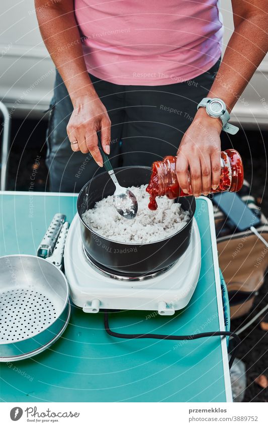 Woman cooking meal on electric stove on camping during summer vacations rice dish lunch outdoor cooking cuisine hot pot female dinner eating recreation trip