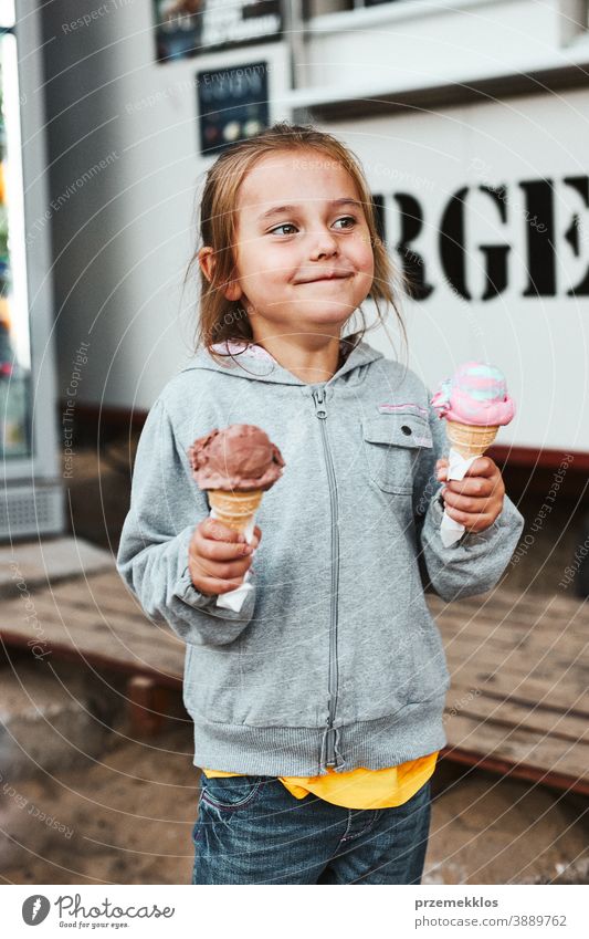 Happy smiling little girl holding two ice cream standing in front of food truck vacation family time family vacation spending time buying shop cafe lifestyle