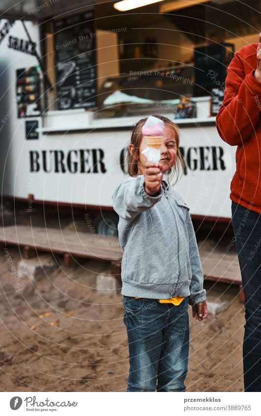 Little girl holding her ice cream in front of her face standing in front of food truck people vacation family time family vacation spending time buying shop