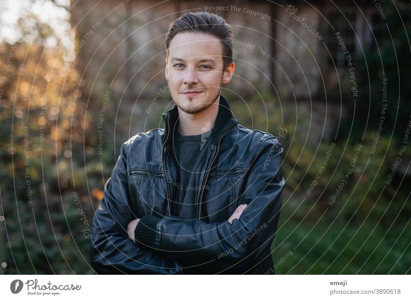 young man in leather jacket outside Outdoors Green masculine more adult Cool (slang) Upper body arms folded Young man Man Friendliness Smiling Positive Impish