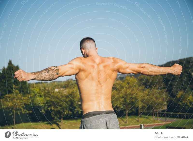 Shirtless Young Man Flexing Biceps And Back Muscles Stock Photo